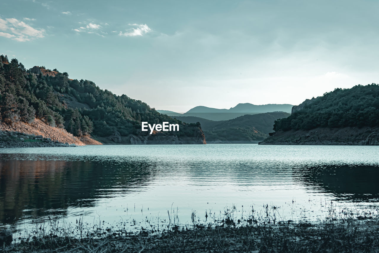 Scenic view of lake by mountains against sky