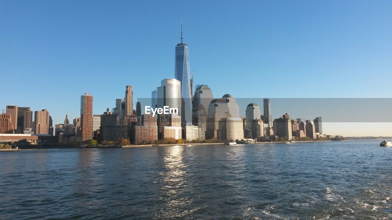 View of skyscrapers by sea against clear sky