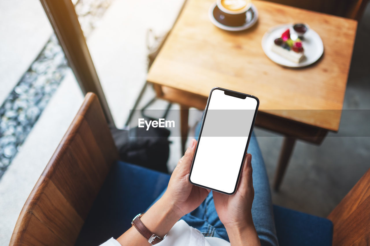 midsection of woman using mobile phone while sitting at table