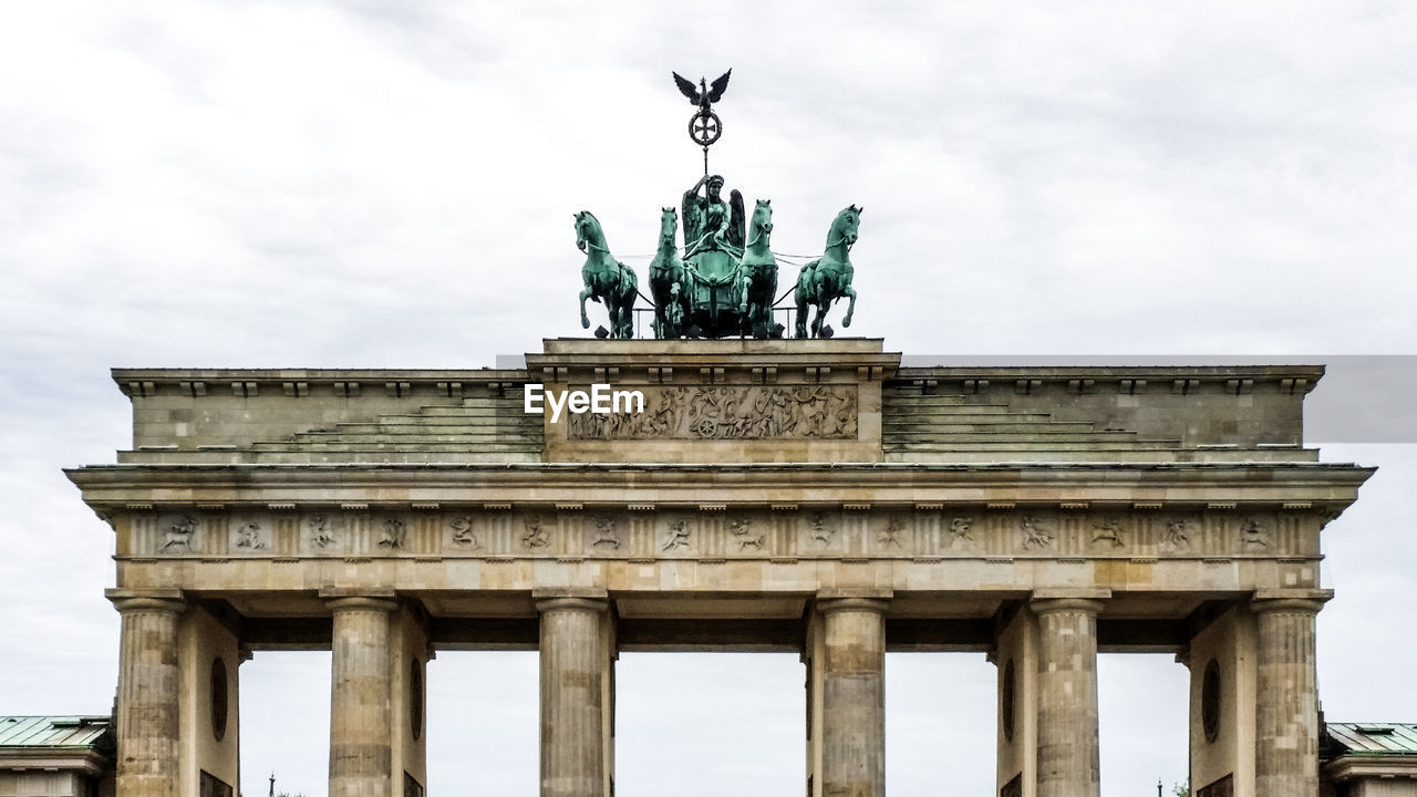 Low angle view of brandenburg tor against cloudy sky