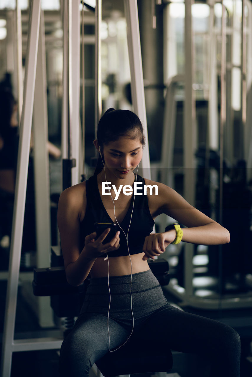 Young woman listening to music at gym