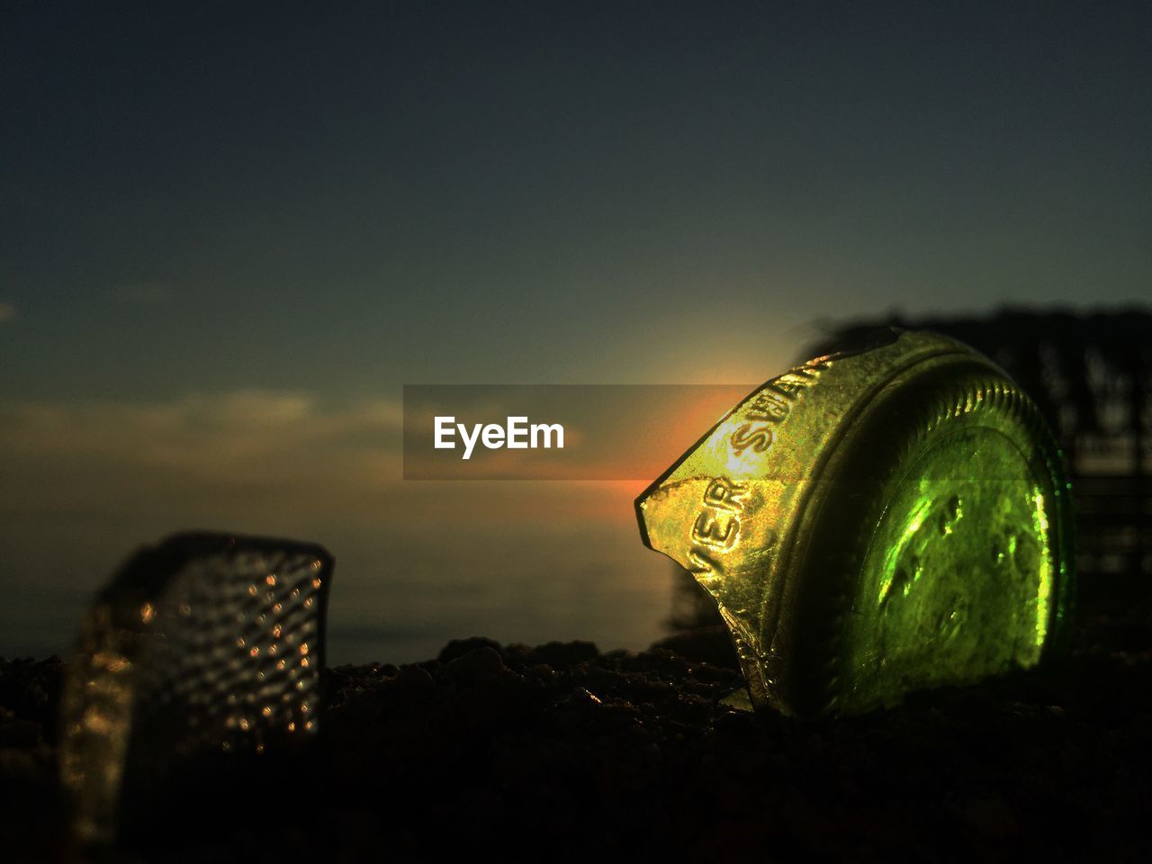 CLOSE-UP OF ILLUMINATED GLASS BOTTLE AGAINST SKY