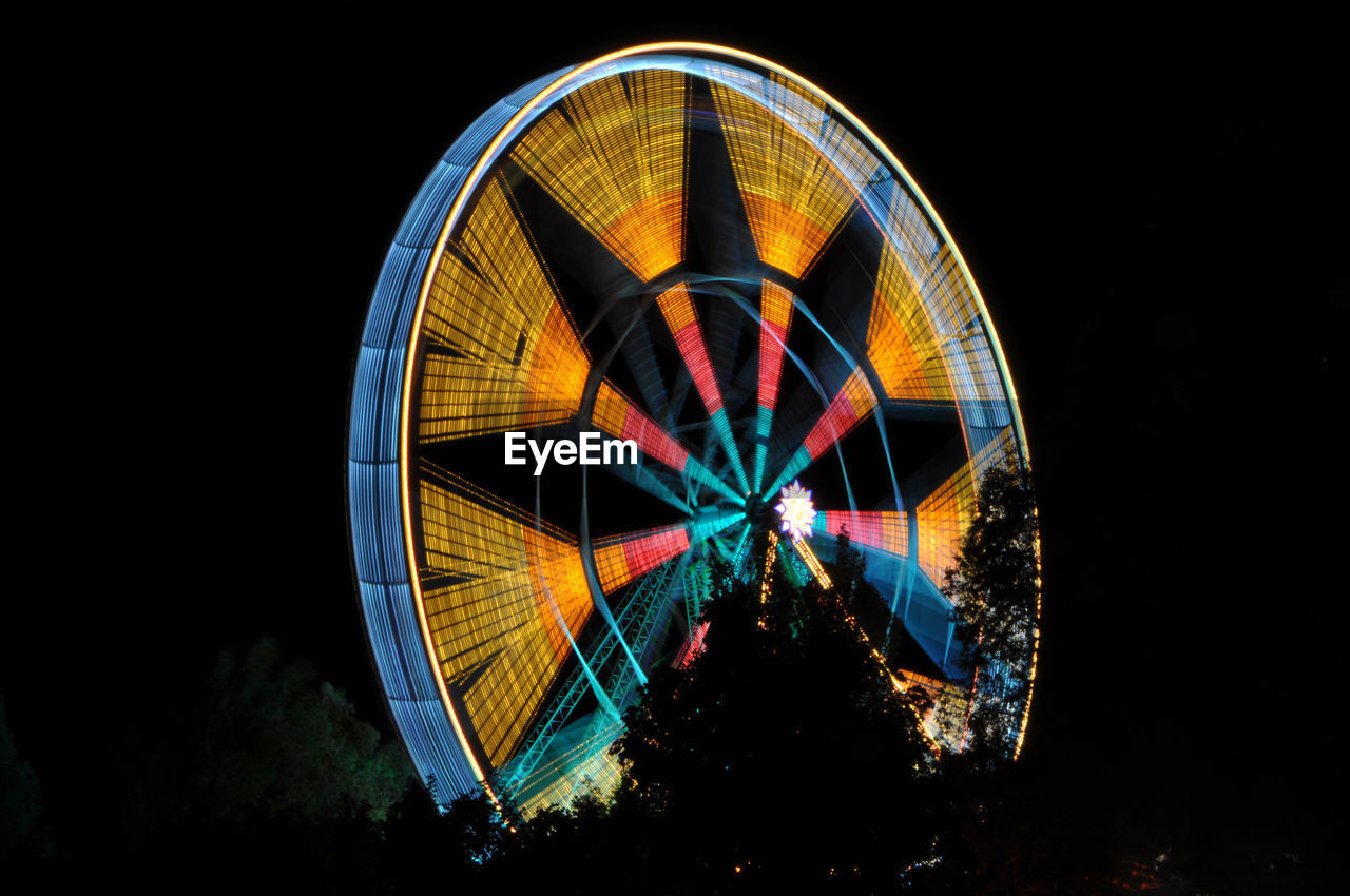 Low angle view of illuminated ferris wheel against sky at night