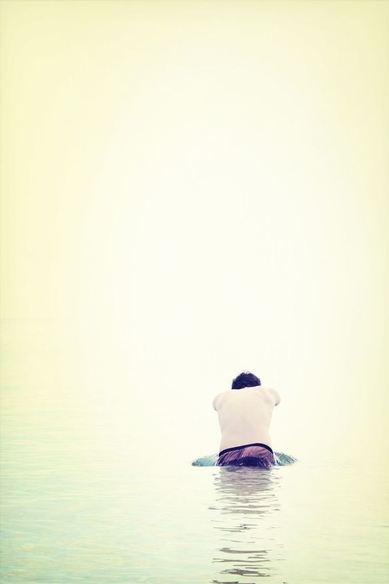 Rear view of man shirtless diving in sea against clear sky