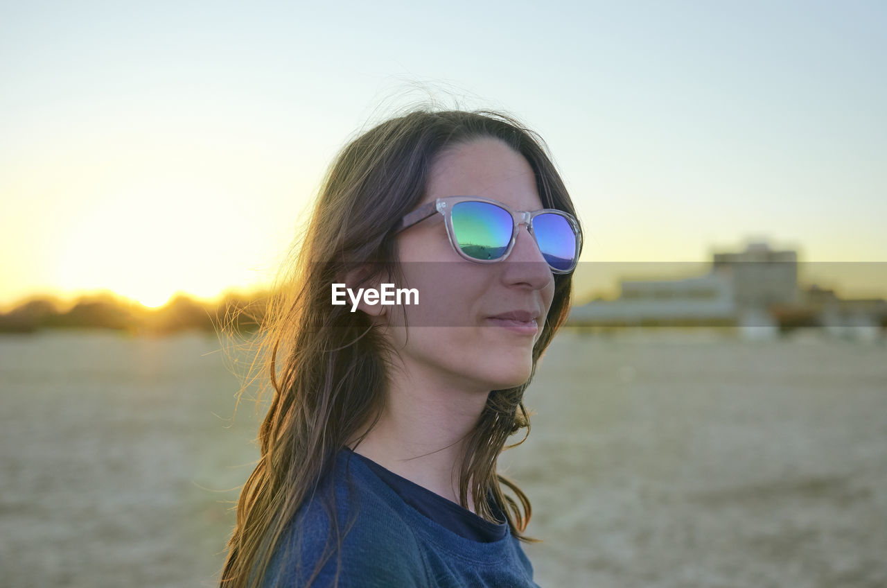 PORTRAIT OF MATURE MAN WEARING SUNGLASSES AGAINST SKY AT SUNSET