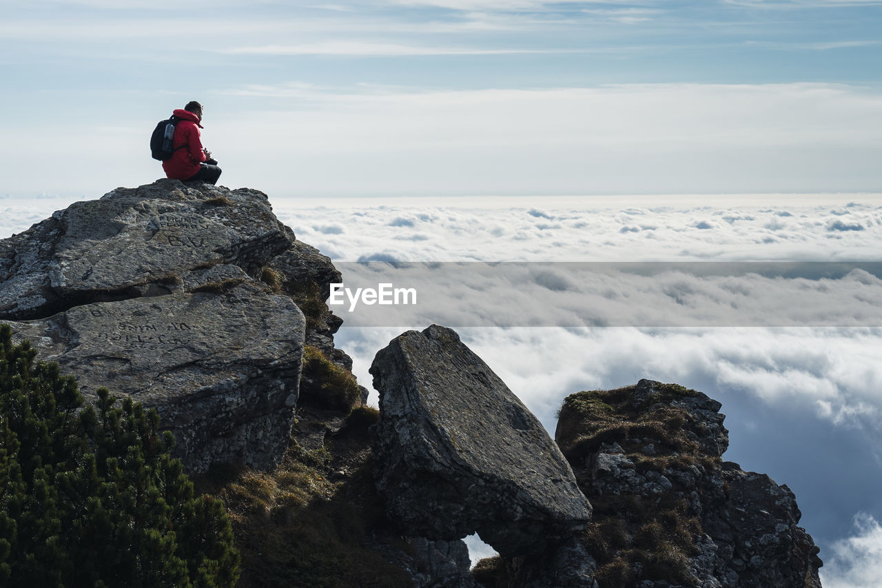 MAN SITTING ON ROCKS AGAINST ROCK FORMATION