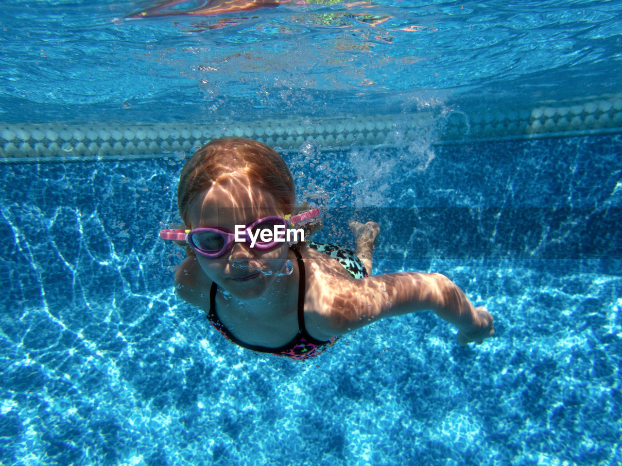 Girl swimming underwater with goggles on