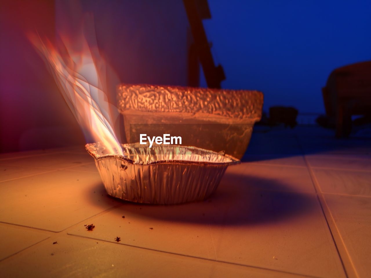 Close-up of lit diya on tiled floor