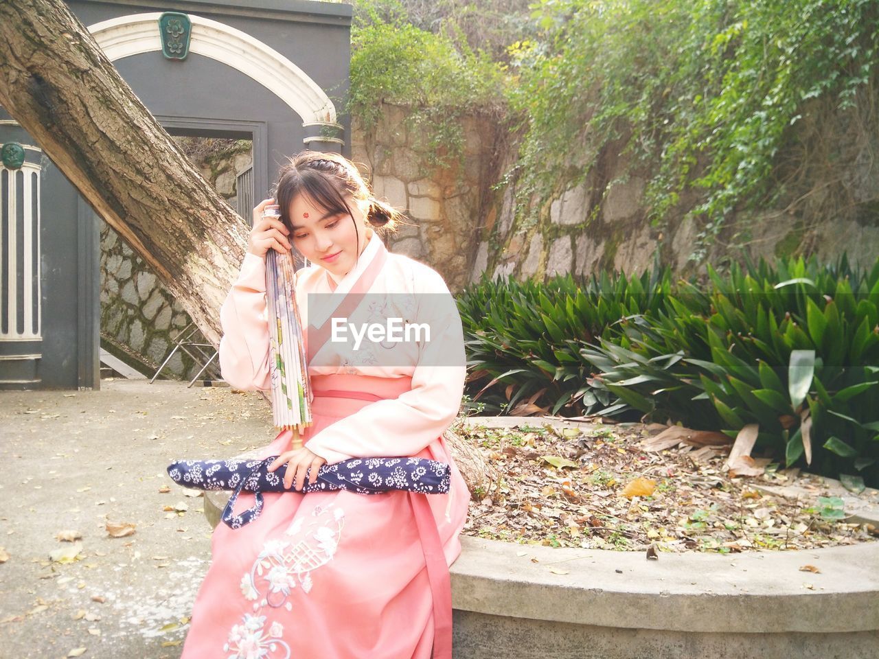 Young woman in kimono sitting at park