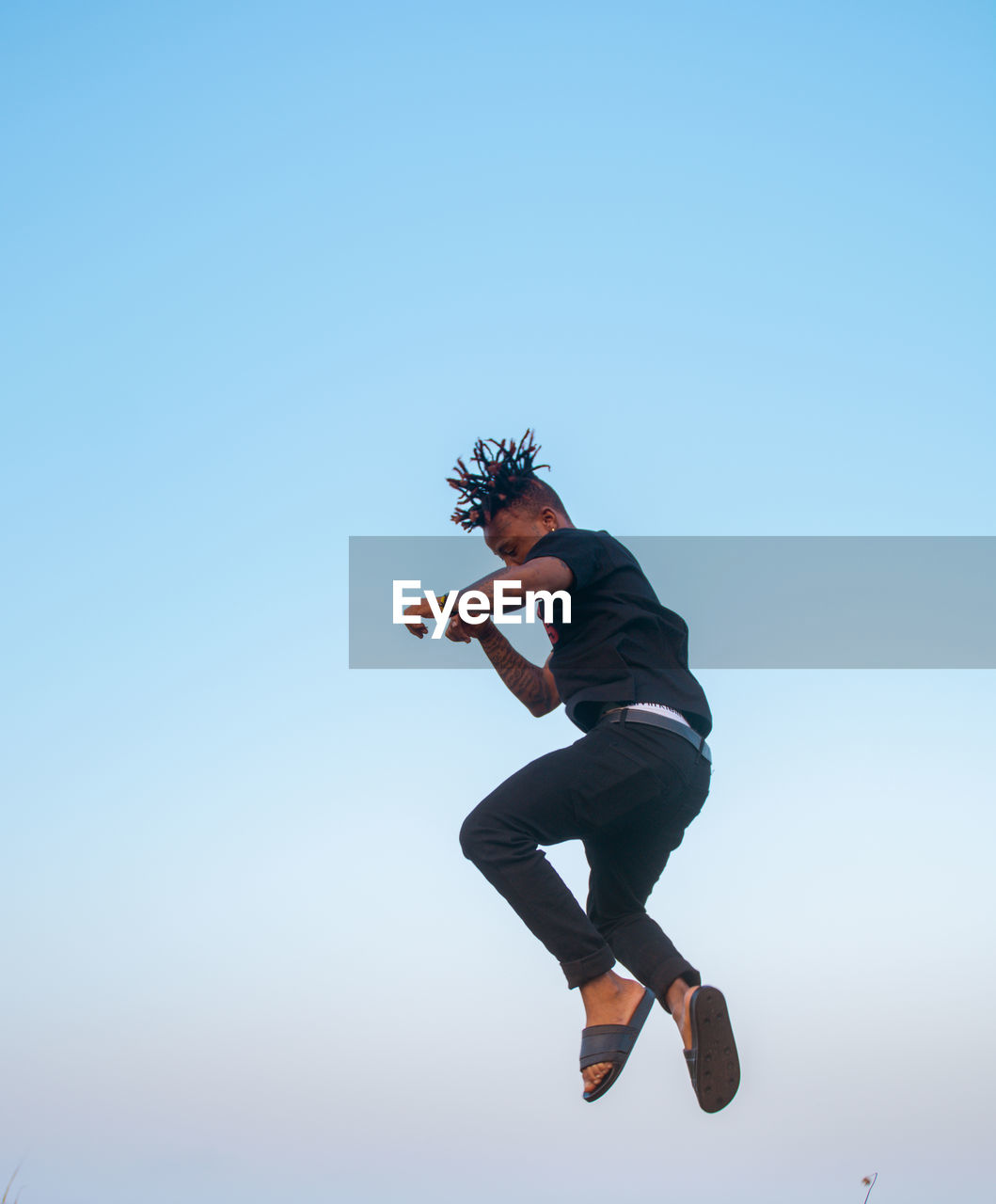 Full length of young man jumping against clear sky