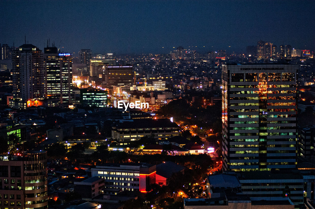 High angle view of illuminated buildings against sky at night