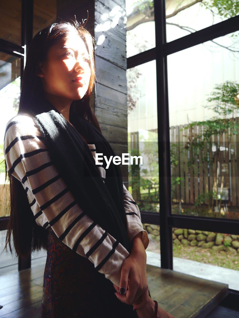 YOUNG WOMAN LOOKING THROUGH WINDOW