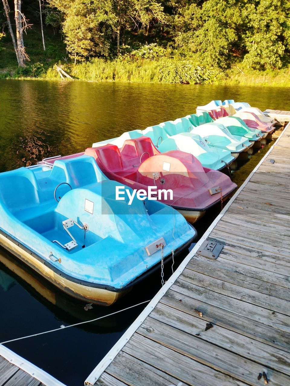 Pedal boats moored by pier at lake