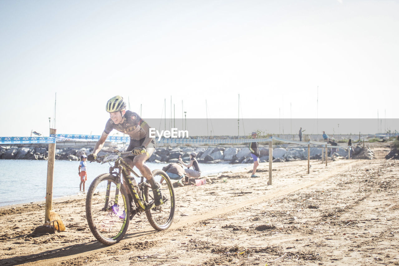 MAN RIDING BICYCLE ON BEACH