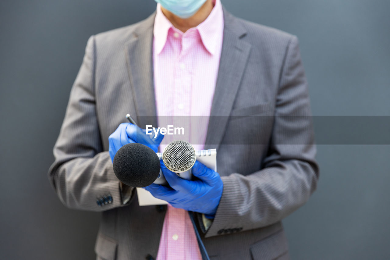 Journalist at news conference wearing protective gloves and face mask against coronavirus covid-19