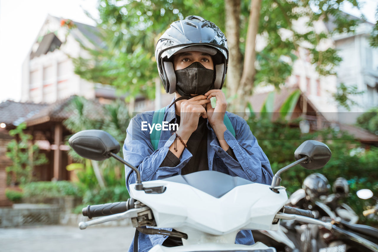 portrait of young man riding motorcycle on road