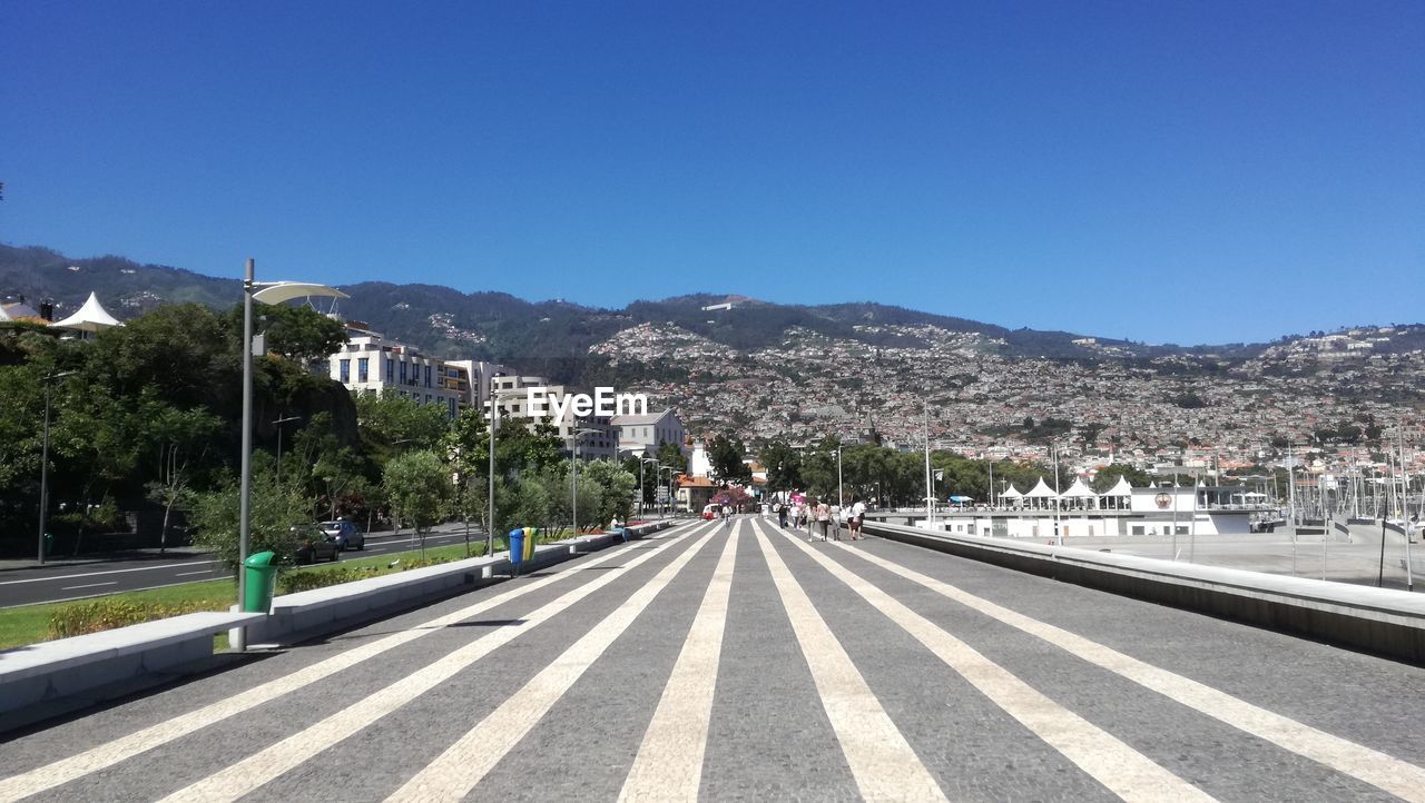 Road by mountains against clear blue sky