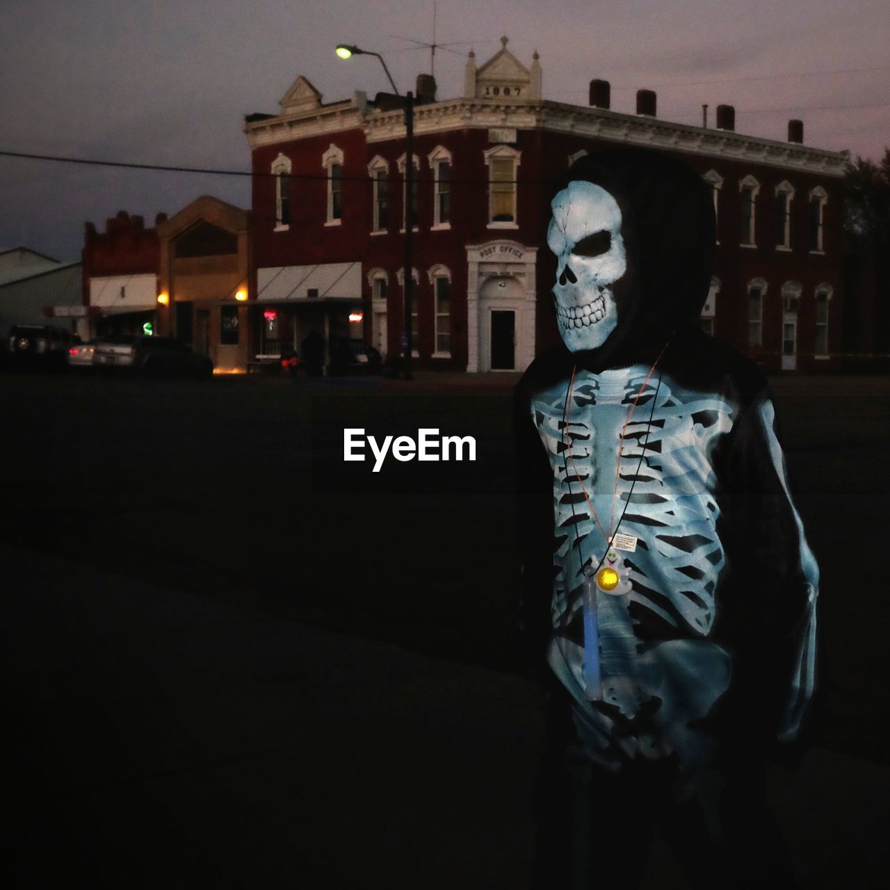 Person in spooky costume standing on street in city at night