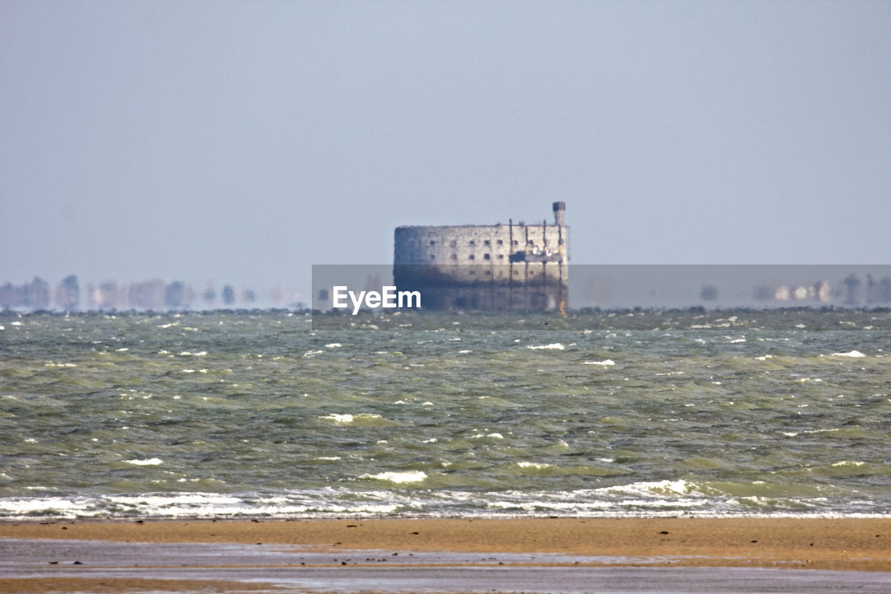 SEA BY CITYSCAPE AGAINST CLEAR SKY