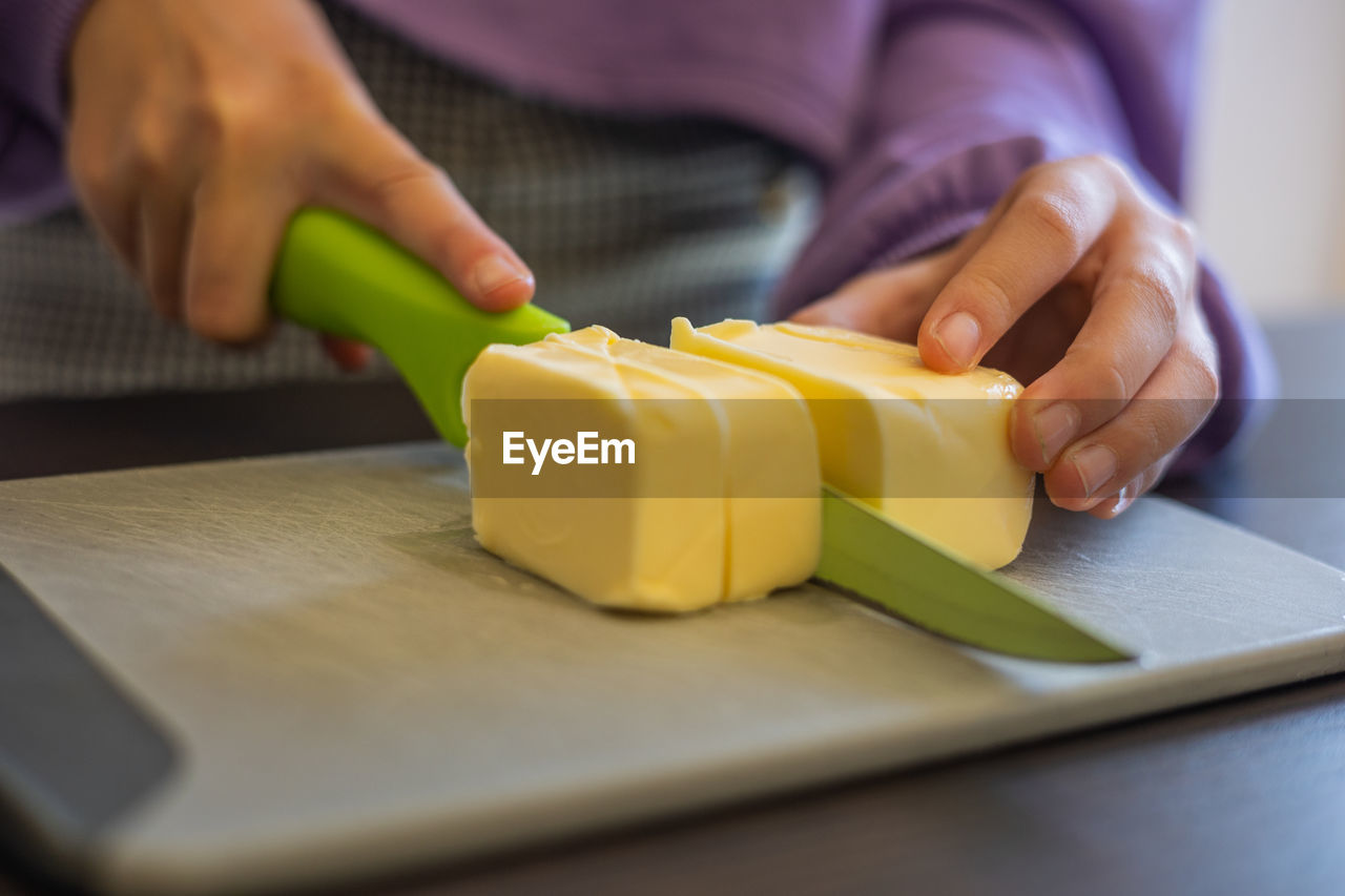 hand, one person, adult, indoors, women, food and drink, food, occupation, yellow, close-up, selective focus, holding, baked, working, business, kitchen, domestic room, domestic life, female, lifestyles, midsection, preparing food, domestic kitchen, freshness, produce
