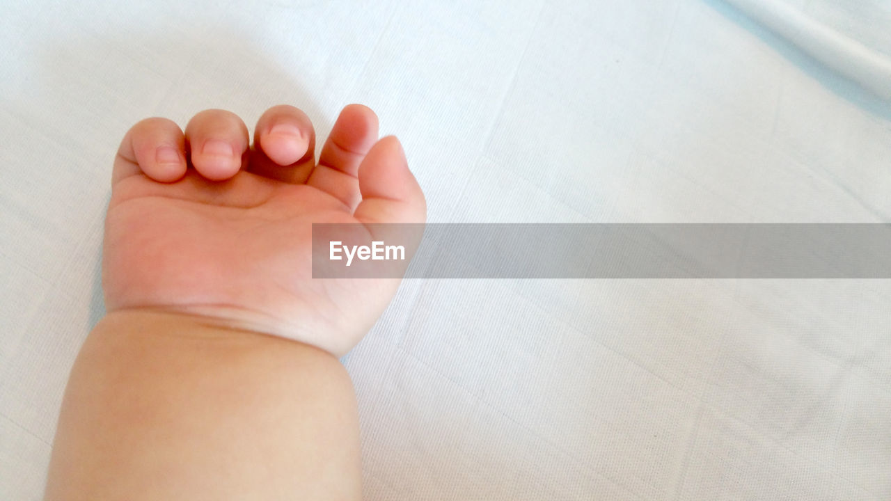 LOW SECTION OF BABY FEET WITH HAND ON FLOOR