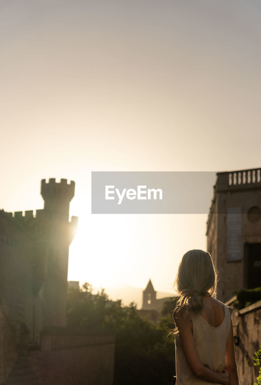 rear view of woman standing against sky during sunset