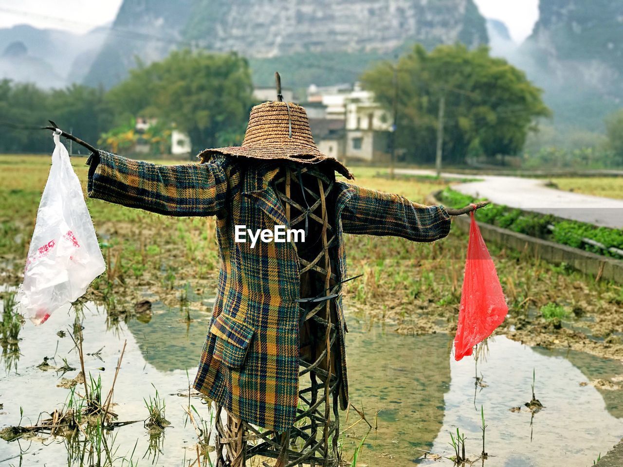 Scarecrow in lake against mountains