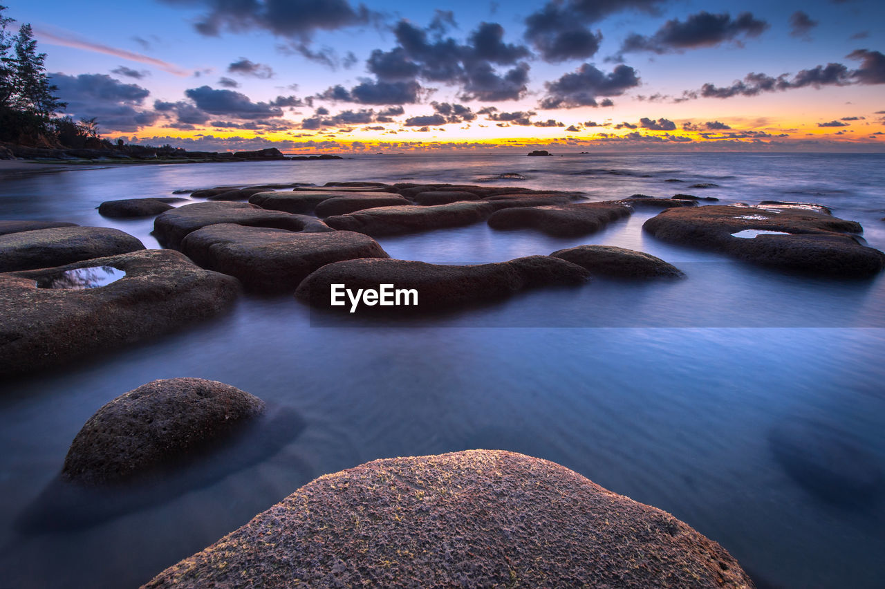 Scenic view of sea against dramatic sky during sunset