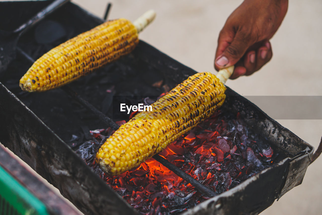 food, sweet corn, food and drink, vegetable, hand, corn, dish, barbecue, freshness, heat, one person, corn kernels, healthy eating, cuisine, barbecue grill, grilled, wellbeing, nature, preparing food, holding, yellow, close-up, outdoors, fish, adult, produce, men