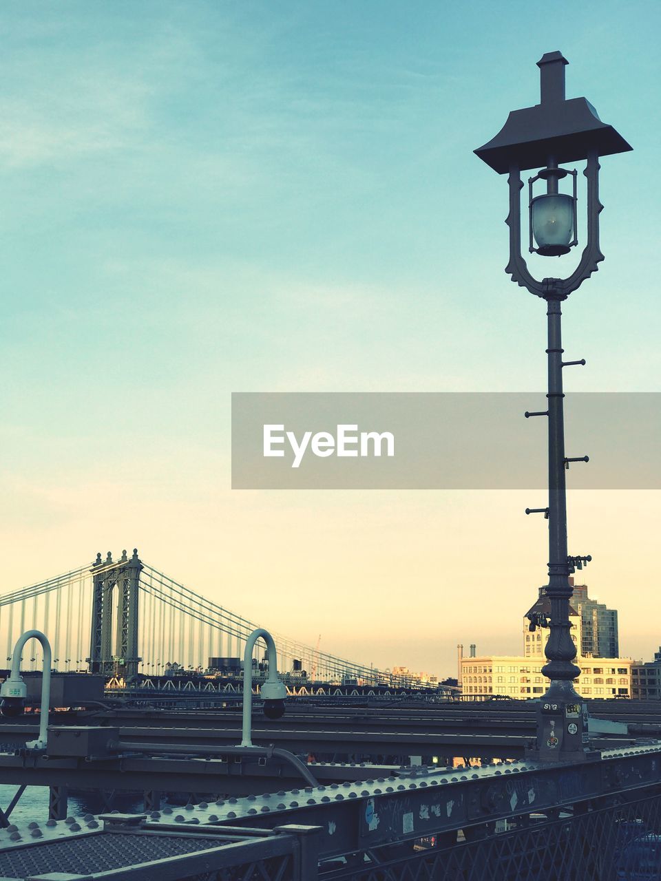 Suspension bridge in city against sky during sunset