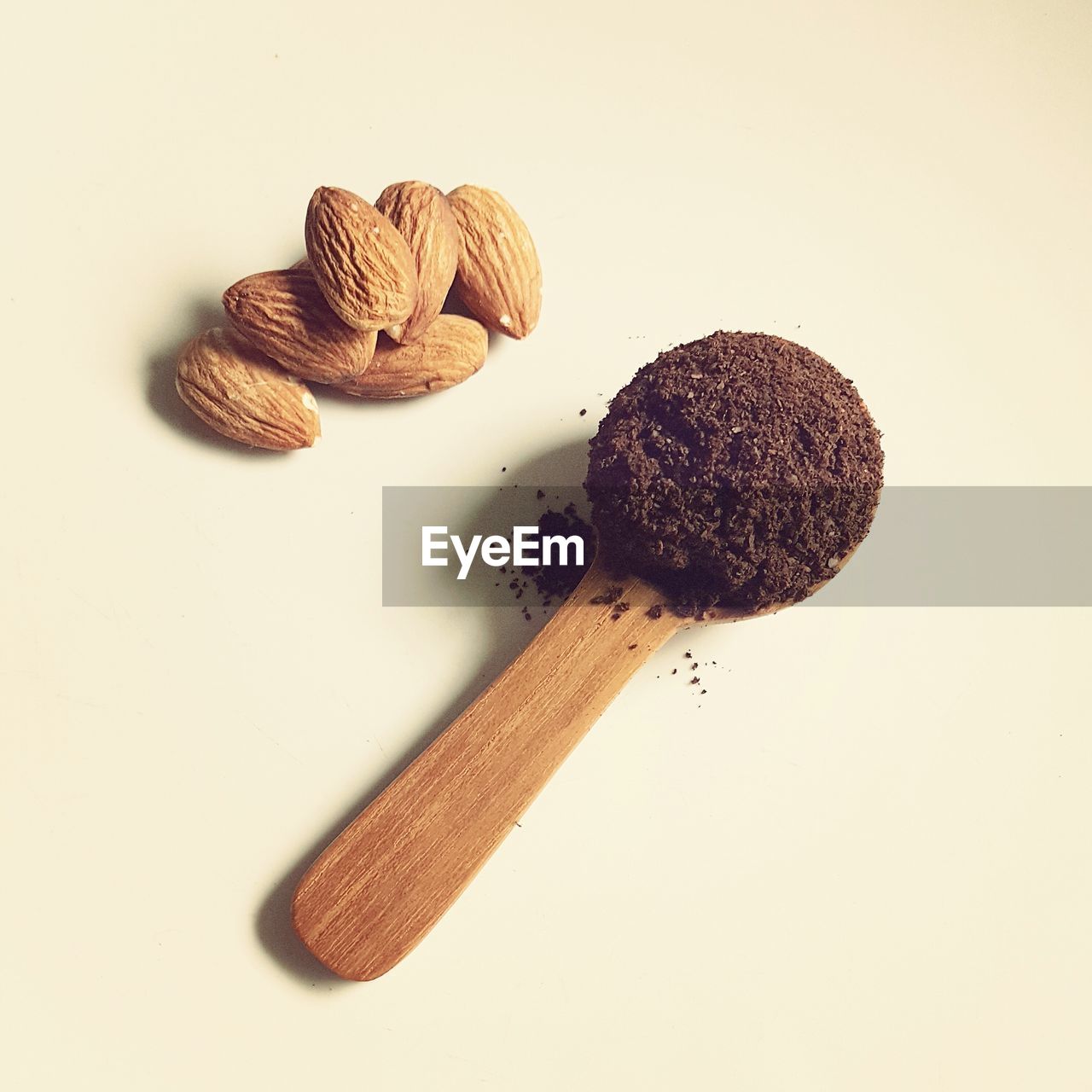 High angle view of coffee powder in spoon by almonds on table