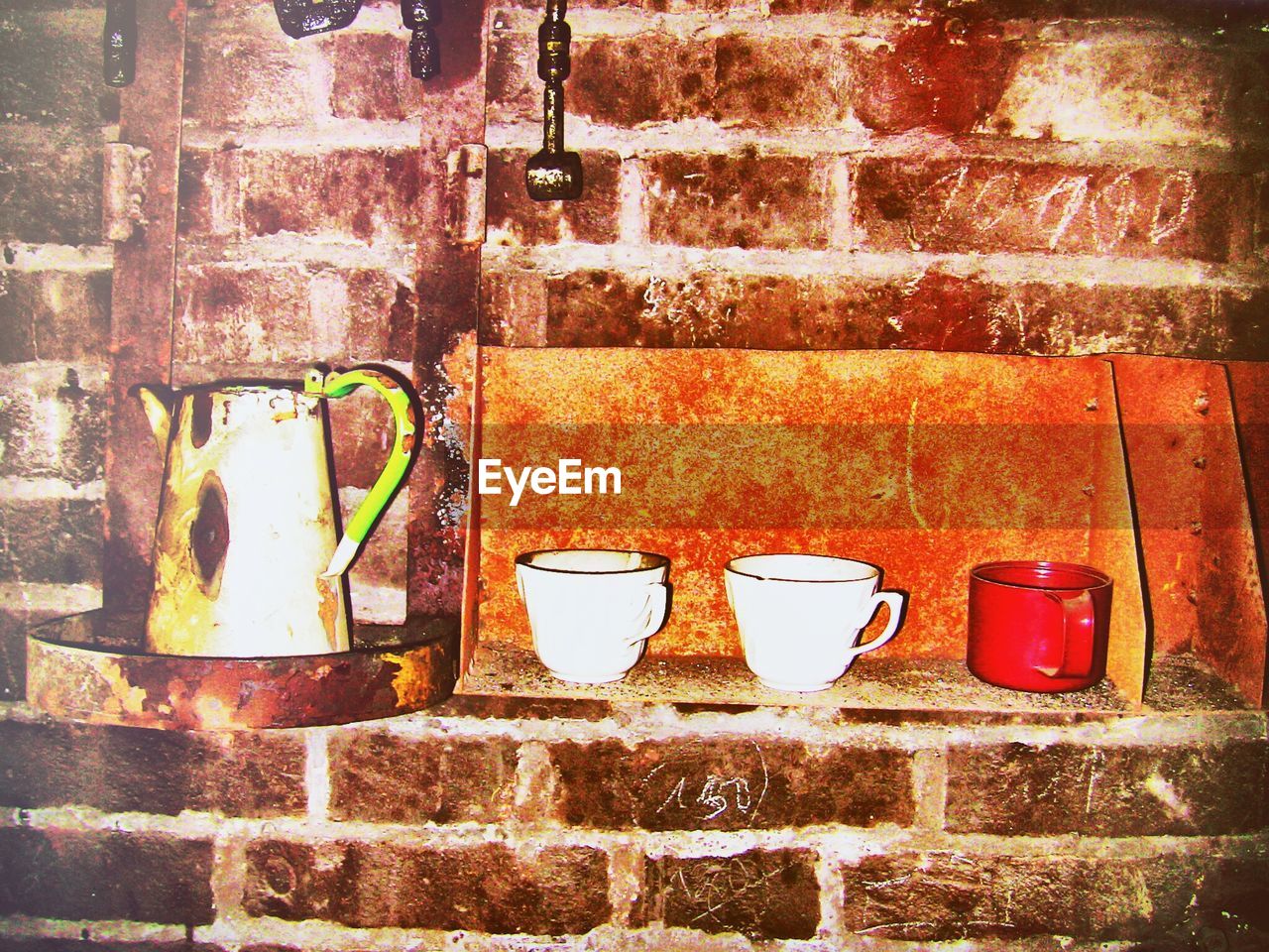 Tea cups and kettle against wall