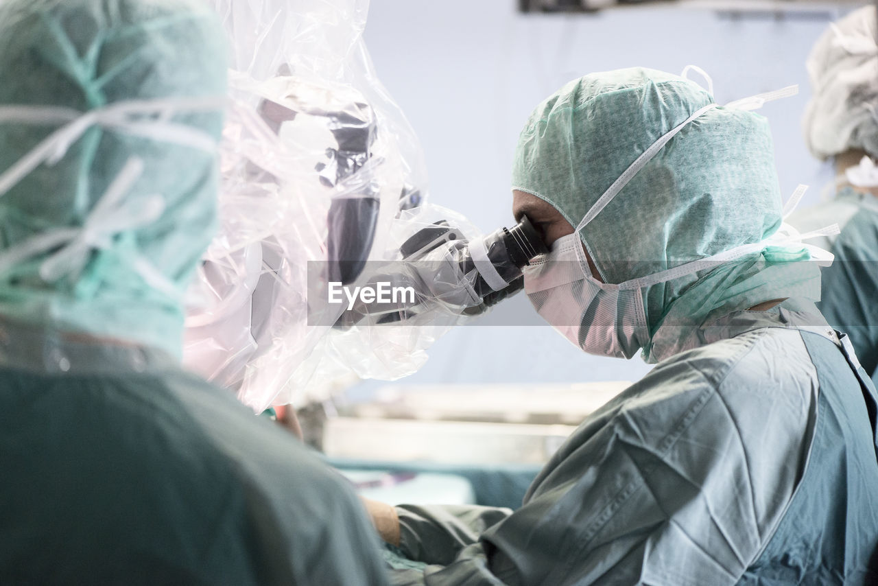 Neurosurgeon looking through microscope during an operation