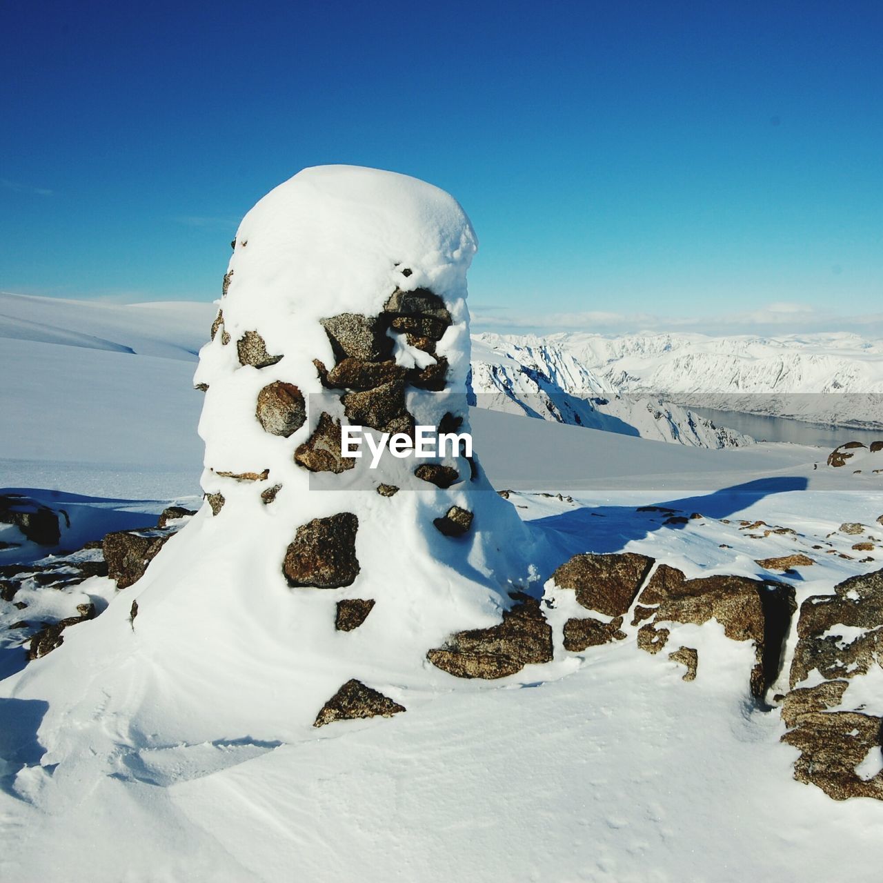 Snow covered landscape against blue sky