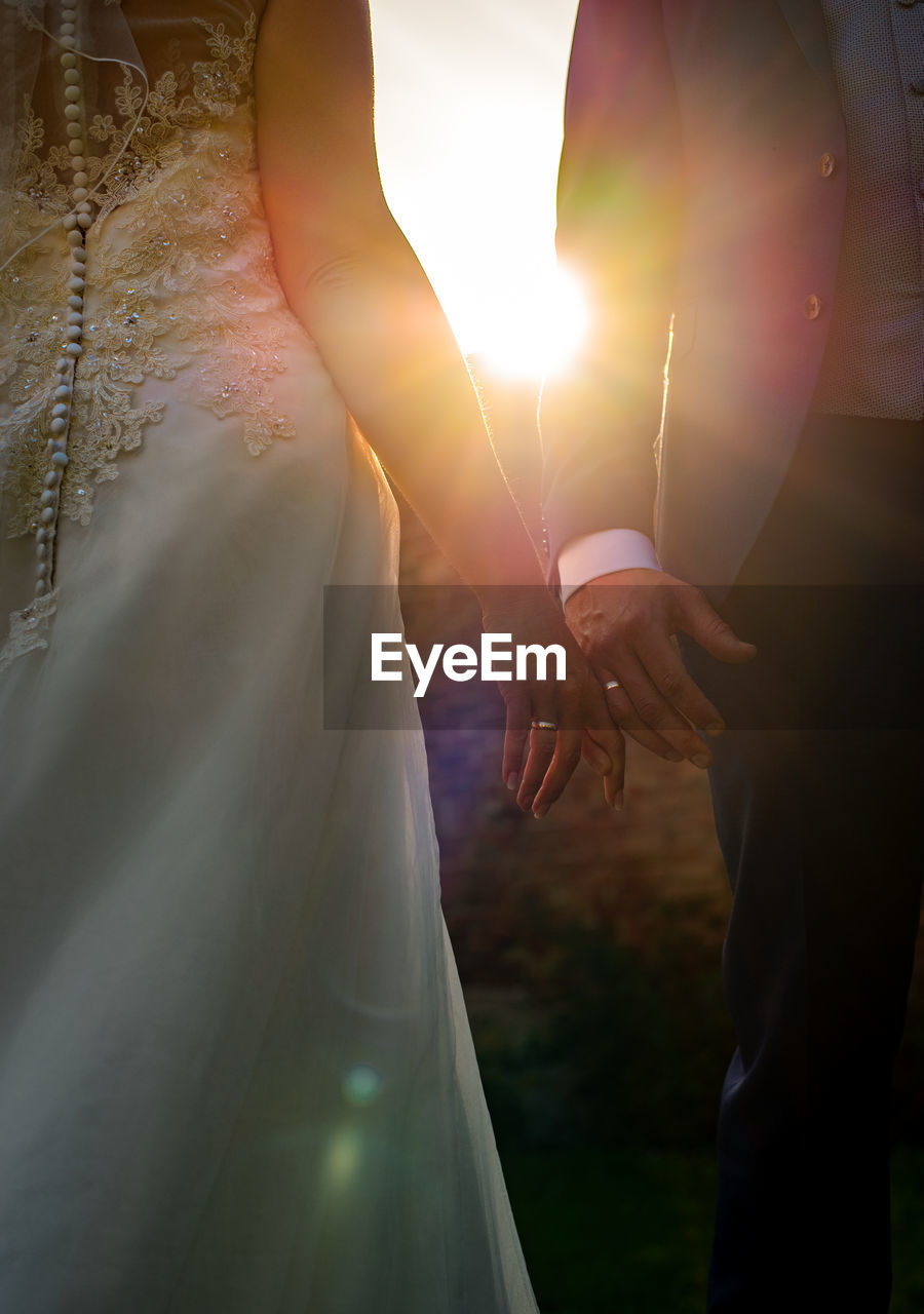 Midsection of bride and groom holding hands