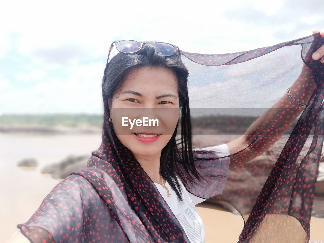 Portrait of smiling woman wearing headscarf against sky