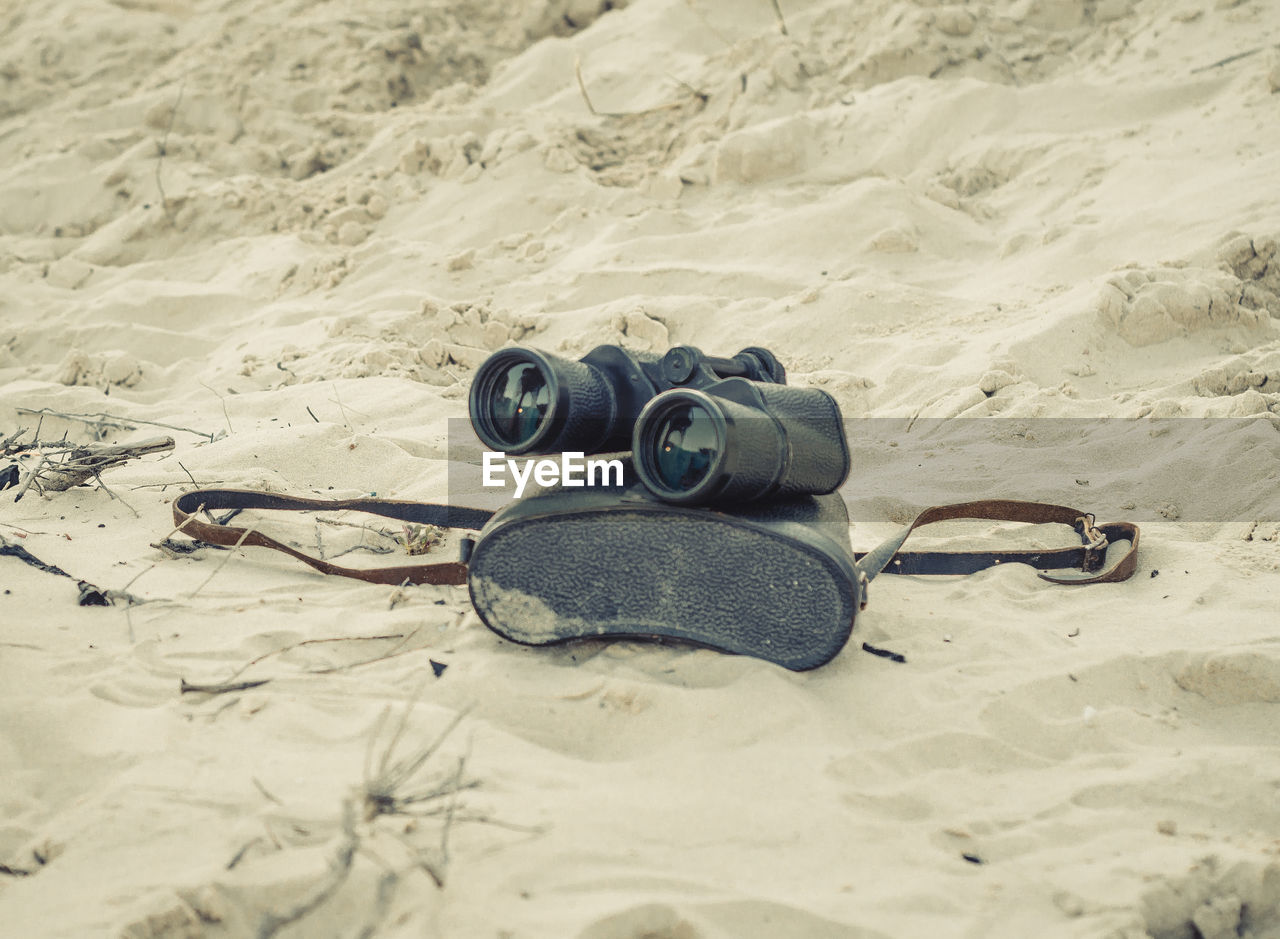 Close-up of binoculars on sand at beach