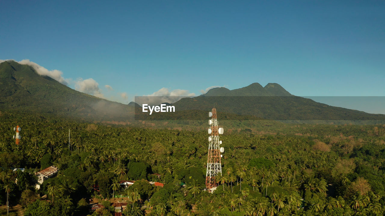 Telecommunication tower, communication antenna against mountains and rainforest, aerial view. 