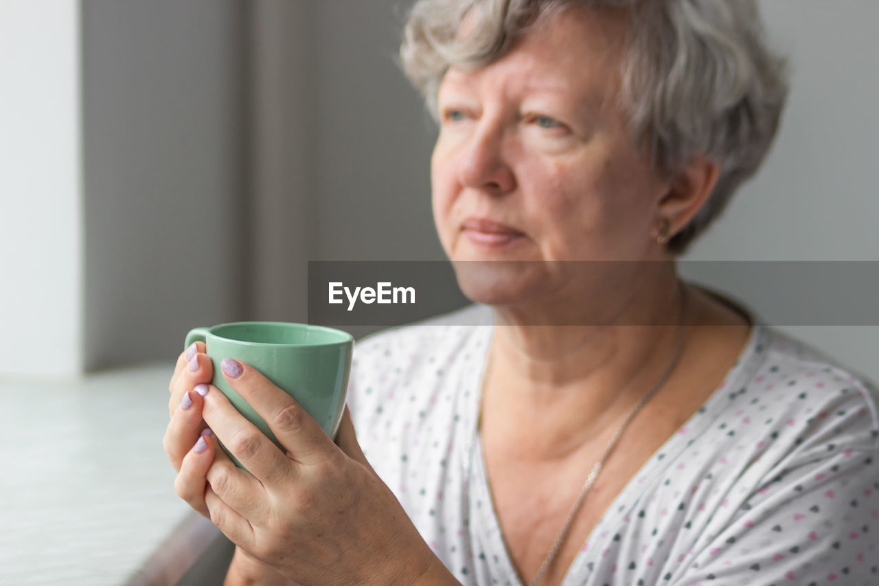 Senior woman holding in her hands mint cup of tea, daily morning routine. lady drinking hot beverage