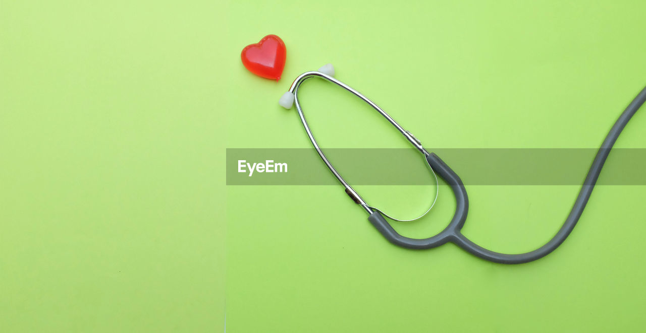 Flat lay red heart white stethoscope on green doctor table.health concept