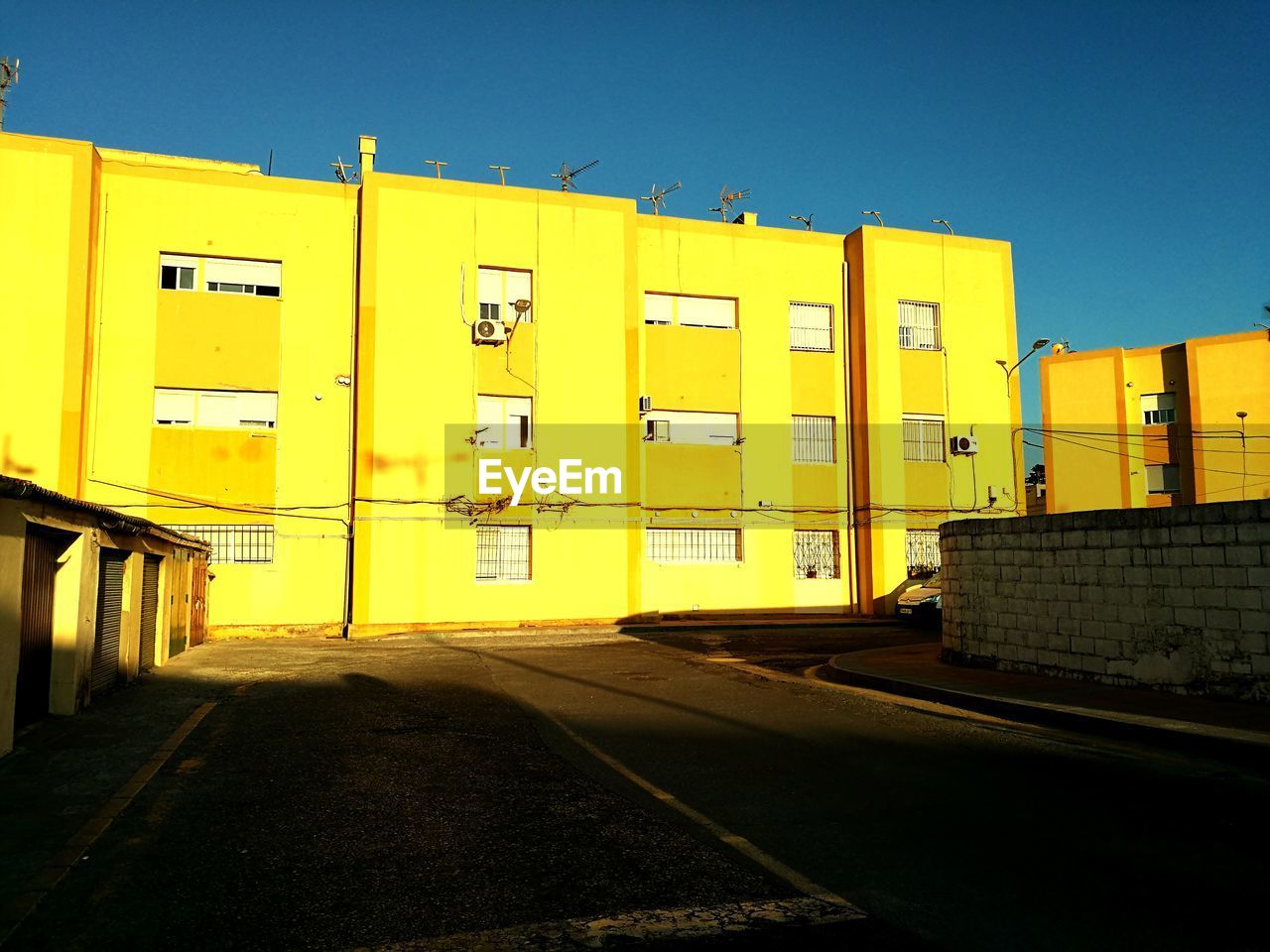 YELLOW STREET BY BUILDING AGAINST SKY