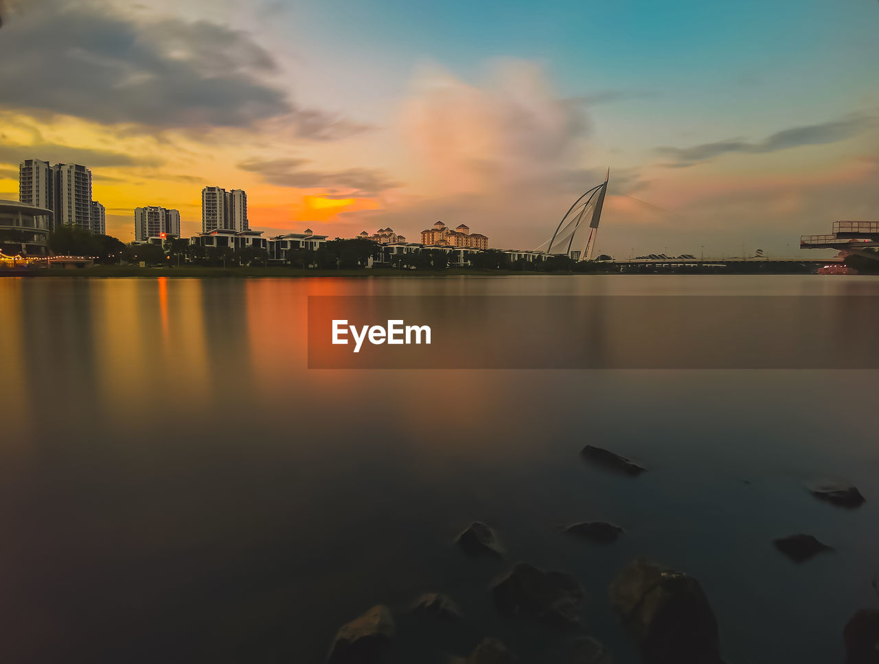 Scenic view of sea by buildings against sky during sunset