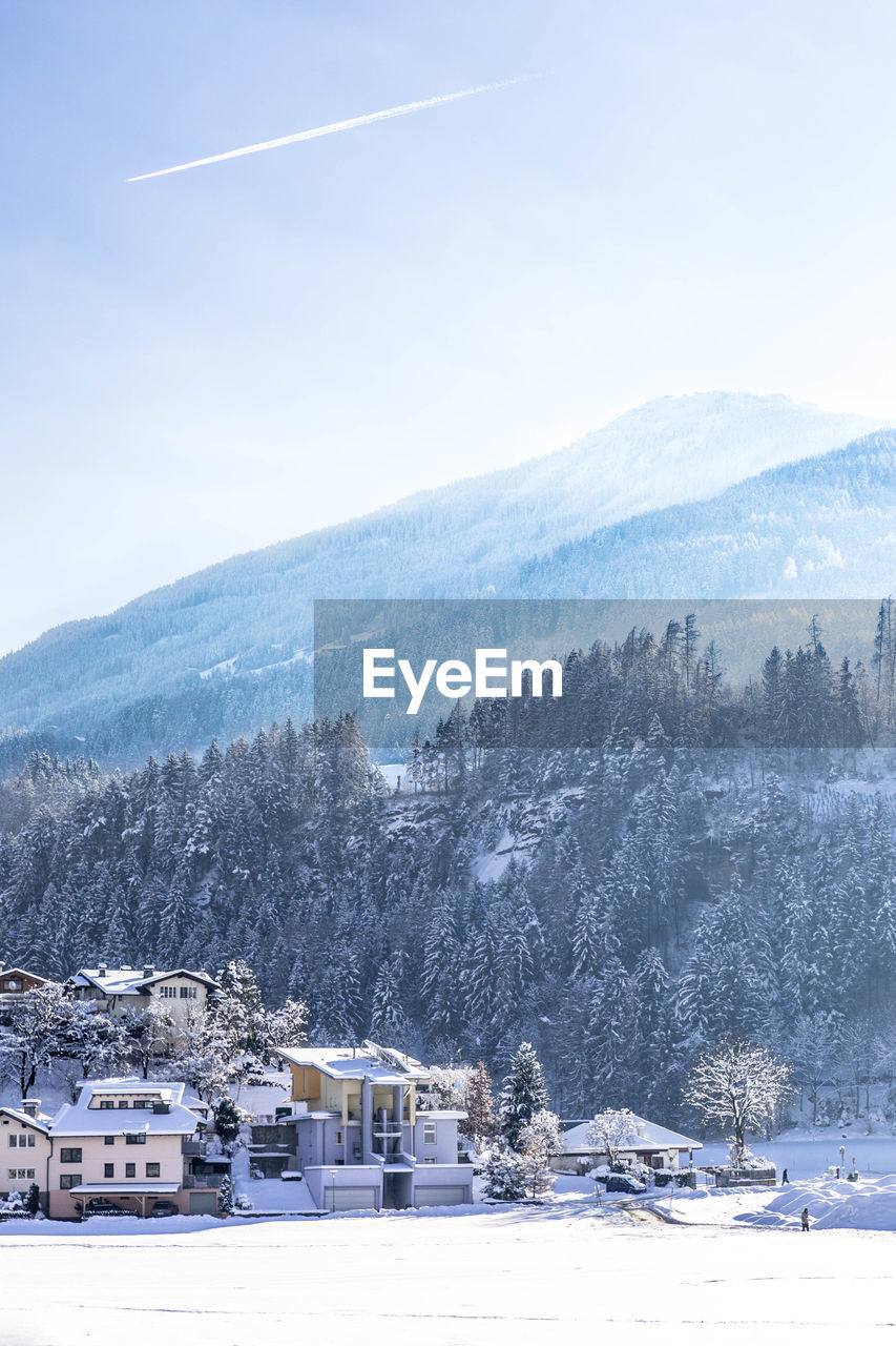 Houses by mountains against sky during winter