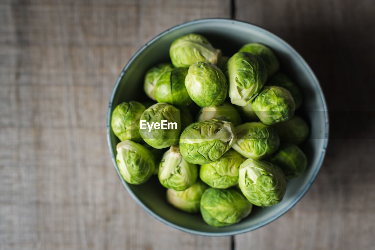 Overhead view of bowl of brussels sprouts on wooden background.