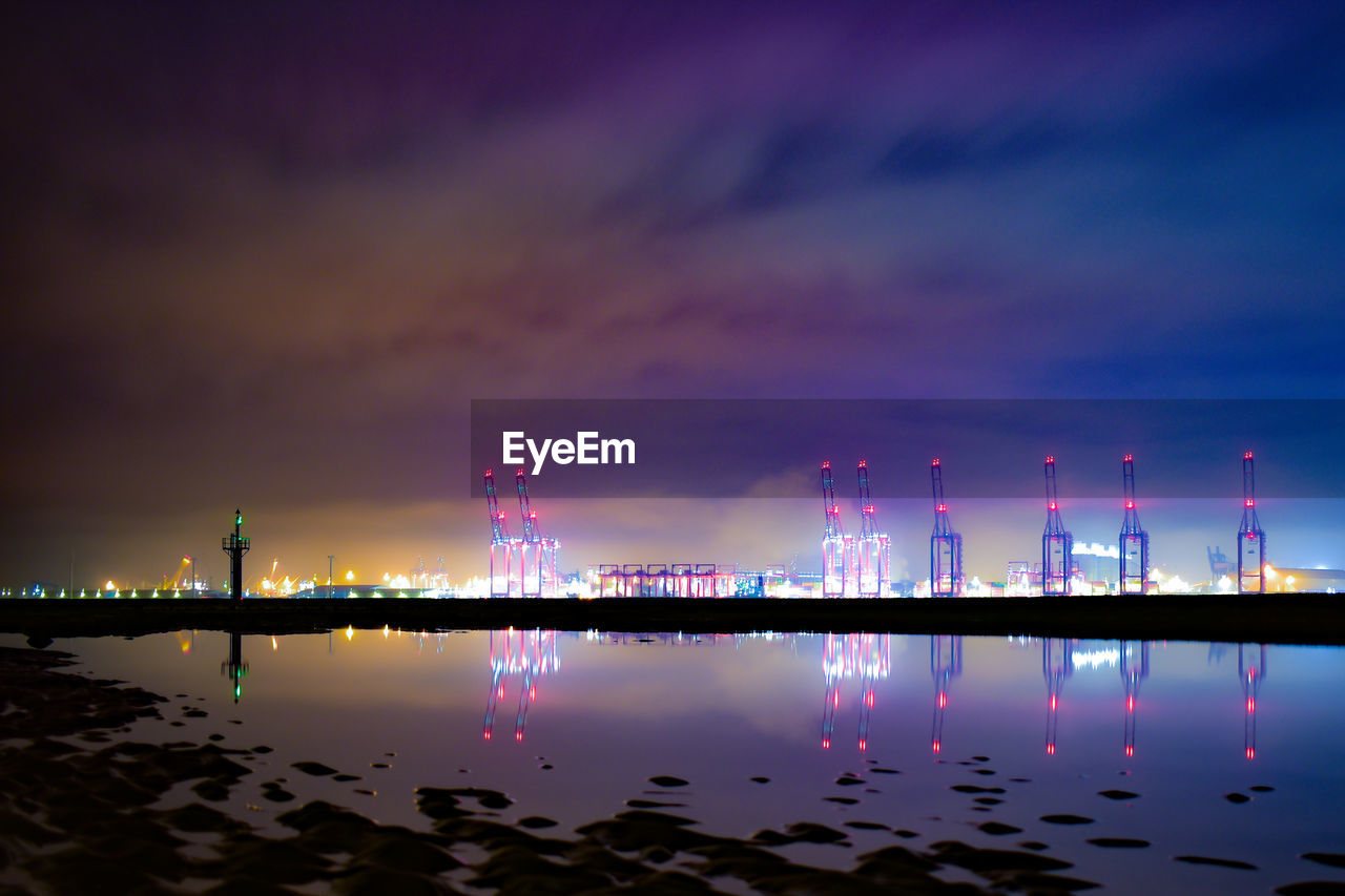 Illuminated bridge over river against sky at night