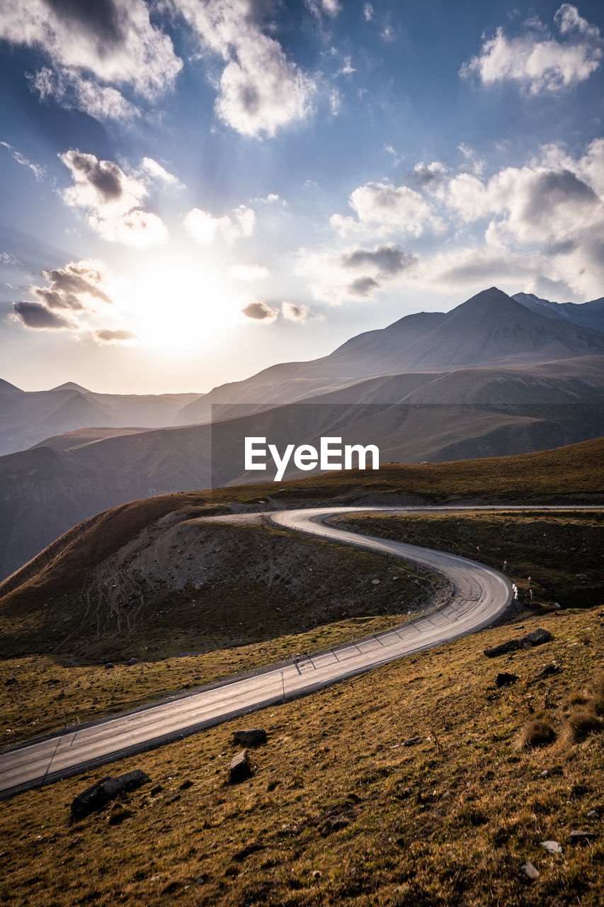 Scenic view of road by mountains against sky