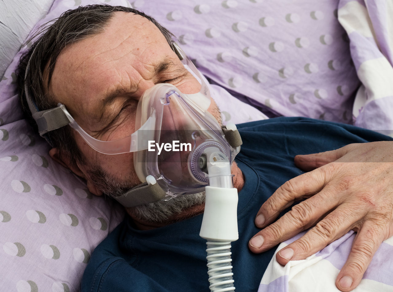 High angle view of senior man with oxygen mask sleeping on bed