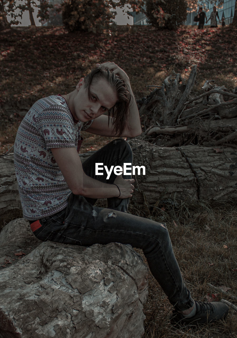 Young man sitting on log