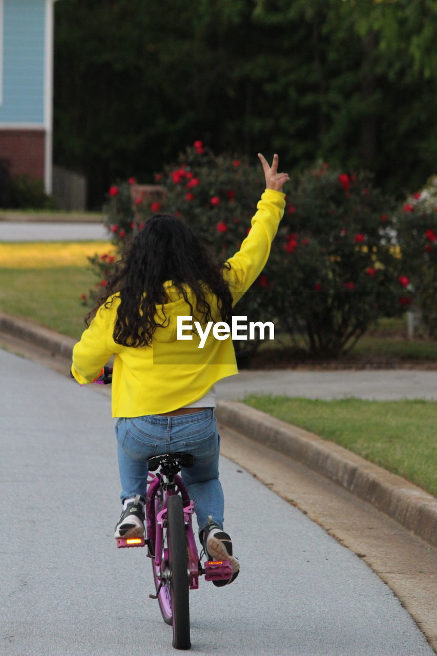 Rear view of girl riding bicycle on road