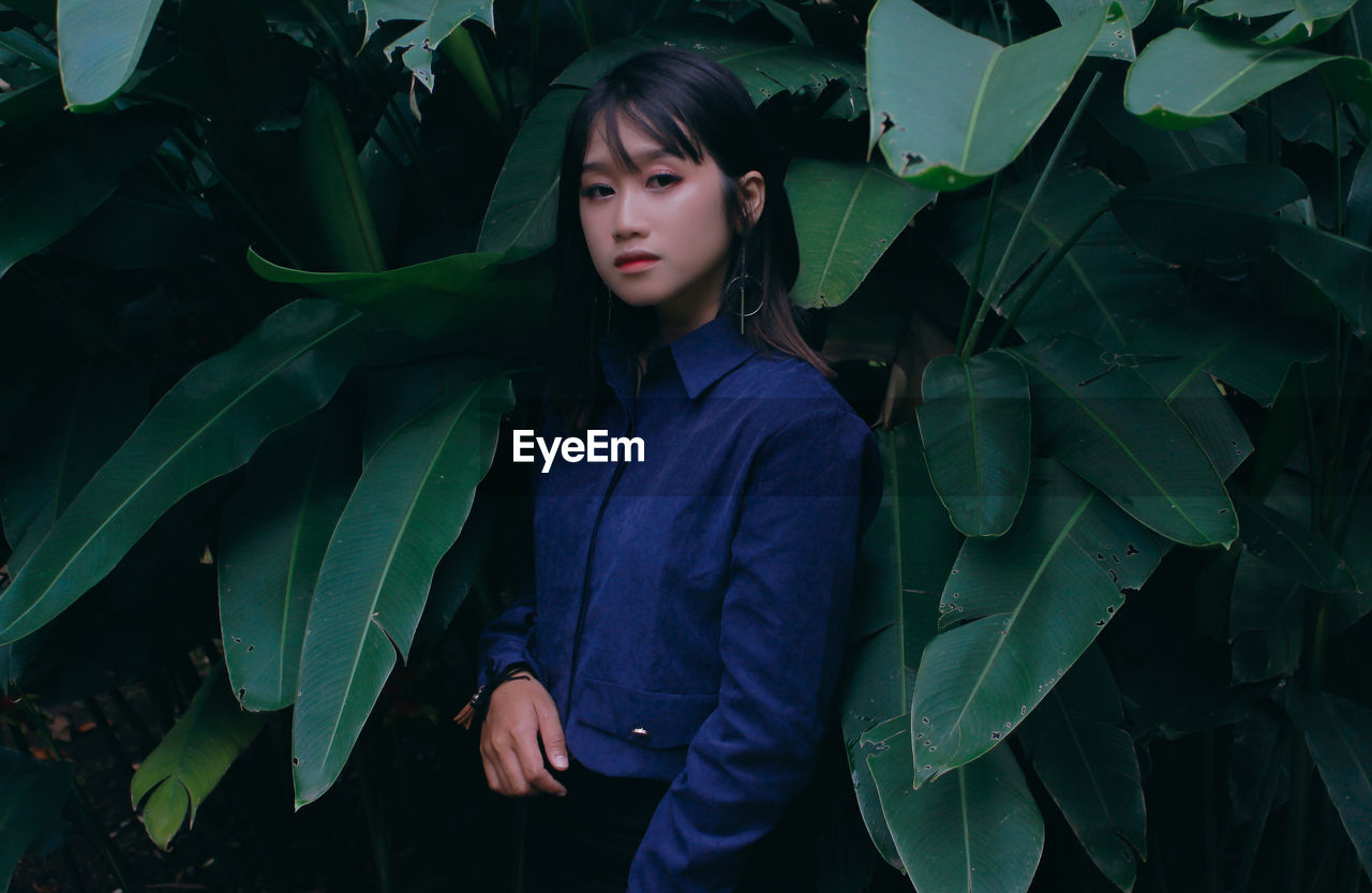 Portrait of serious girl standing by plants